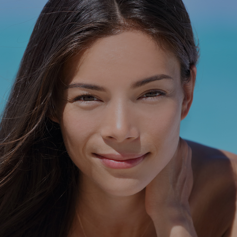 Asian woman wearing bikini and jewelry - bracelet and necklace - relaxing on beach. Portrait of Chinese Caucasian multiracial fashion model lying down on white sand on Caribbean vacation travel.